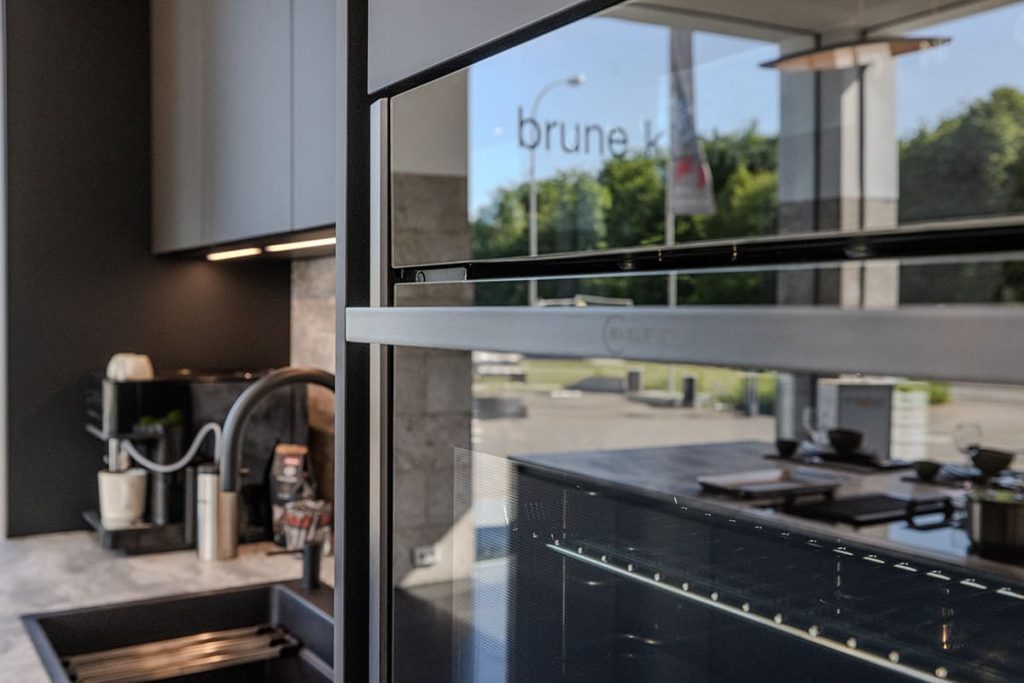 Küche mit Einbauofen, dunklen Fronten und Arbeitsfläche in Steinoptik