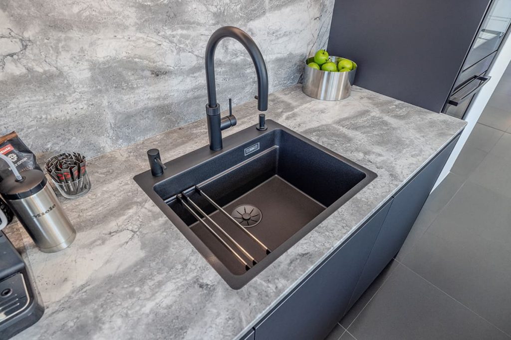 Schwarze Küchenspüle mit schwarzer Armatur und Arbeitsplatte in Steinoptik